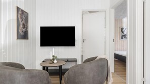 Ein modernes Wohnzimmer mit Flachbildfernseher, einem runden Tisch mit Dekoration und einem Sofa.