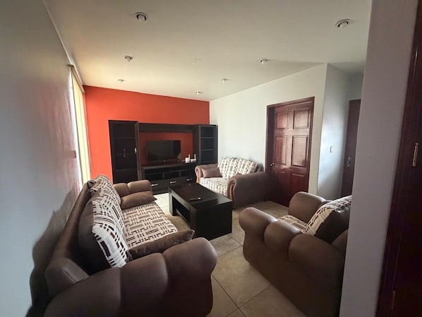 Una sala de estar con un sofá, una mesa de centro y un televisor.