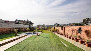Área residencial com gramado bem cuidado, piscina e muros de tijolo.