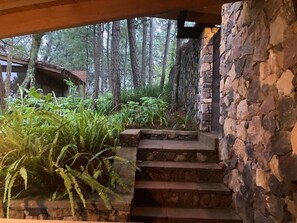 A stone staircase leading to a covered area with a forest backdrop.