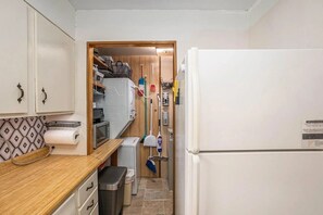 Eine kompakte Küche mit Mikrowelle, einem kleinen Mülleimer und einem Kühlschrank.
