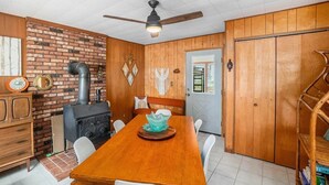 A dining area with a brick wall, a wood-paneled door, and a ceiling fan. - Cozy 2-bedroom cottage in Bitely perfect for a relaxing getaway. (Bitely)
