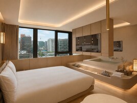 Una habitación de hotel moderna con una cama grande, una bañera integrada y vistas a la ciudad.