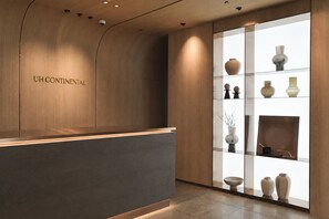 Un mostrador de recepción con detalles de madera y el texto 'UH CONTINENTAL' en la pared.