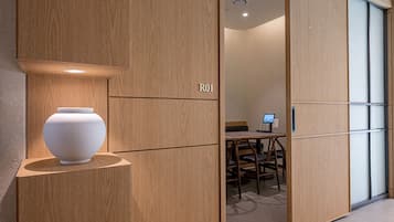 A modern interior with a wooden partition labeled 'R01', a white vase on a shelf, and a desk with a computer monitor.