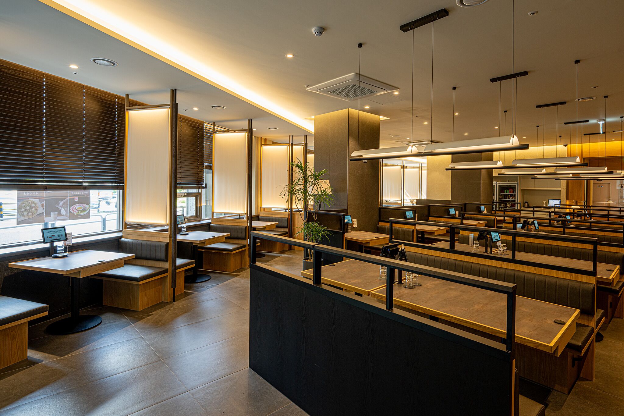 A modern restaurant interior with booths, tables, and a counter.
