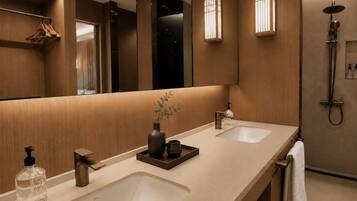 Een moderne badkamer met twee wasbakken, een spiegel, een douche en een handdoekrek.