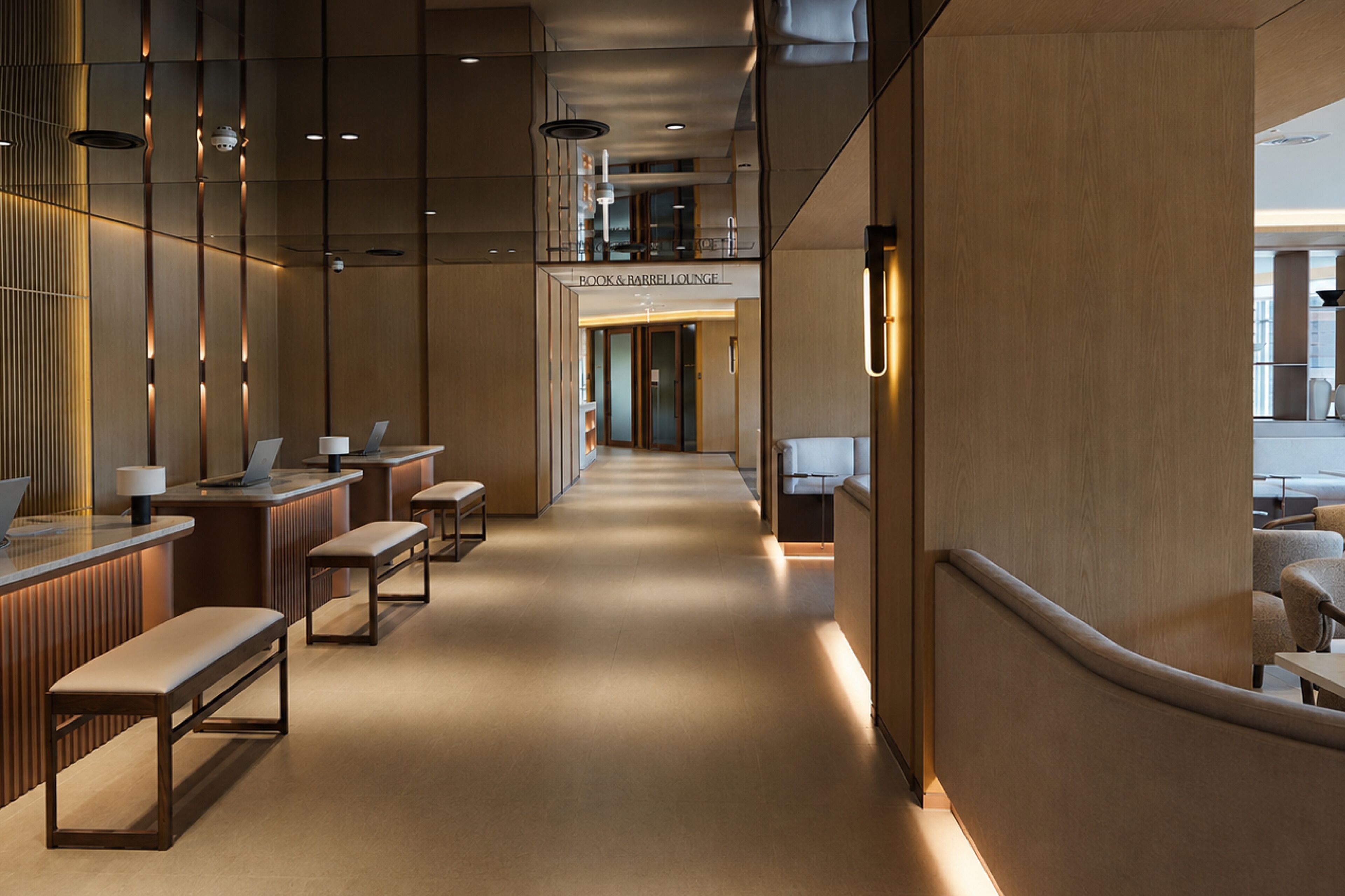 Un moderno vestíbulo de hotel con un área de estar central, disposición de asientos y una recepción.