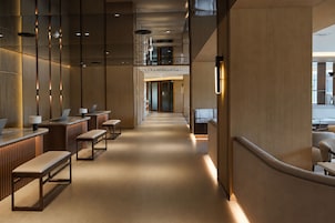 A modern hotel lobby with a central lounge area, seating arrangements, and a reception desk.