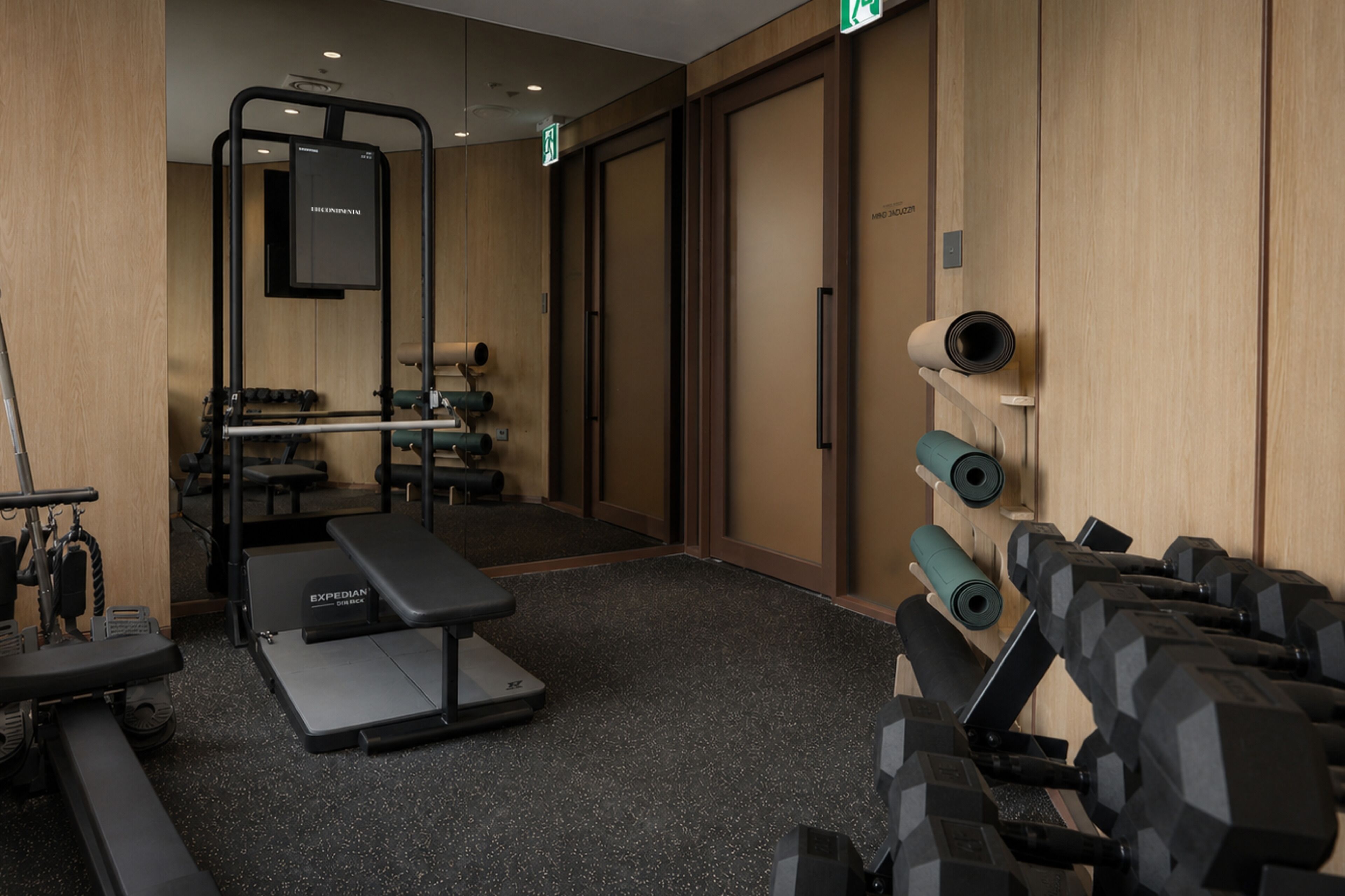 A gym with exercise equipment, a bench, and a wall-mounted TV.