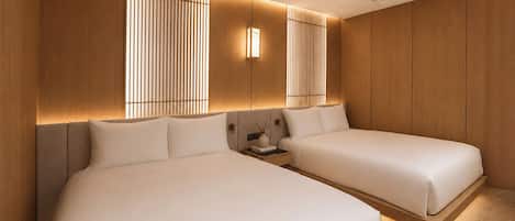 A modern hotel room with two beds, wooden paneling, and a nightstand with a vase.
