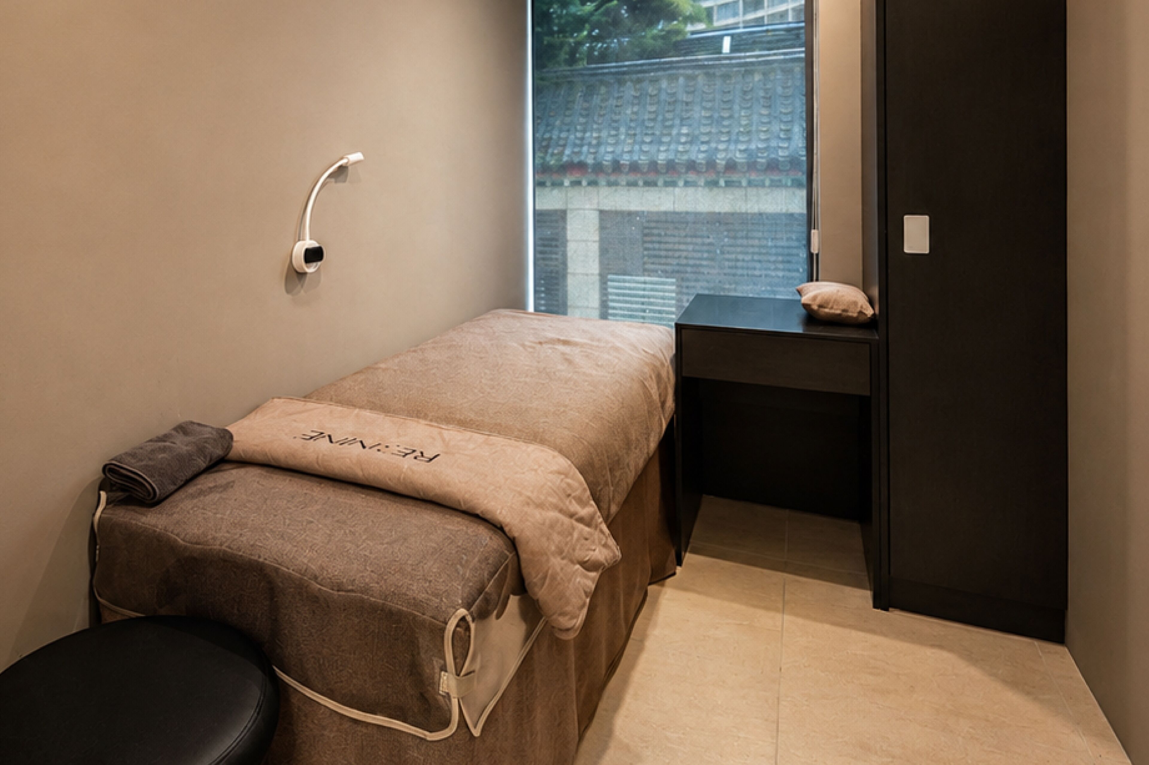 A small, private room with a bed, a desk, and a chair.