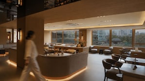 A modern interior with a reception desk, seating area, and large windows offering city views.