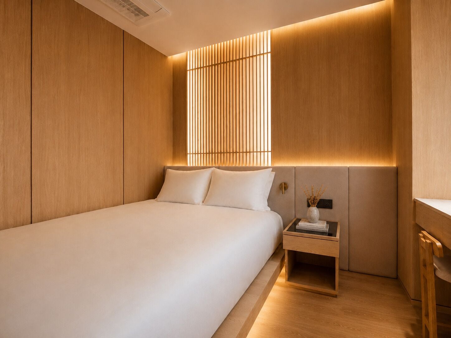 Un dormitorio moderno con una cama grande, una mesita de noche con un florero y un espacio de escritorio.