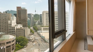 A view from a hotel room window overlooking a cityscape with modern buildings and a prominent tower.