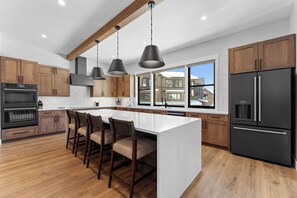 A modern kitchen with wooden cabinets, a large island, and a black refrigerator.