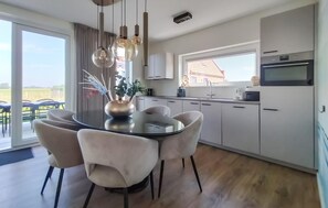 Une cuisine moderne avec un coin repas, de grandes fenêtres et une vue sur l’extérieur.