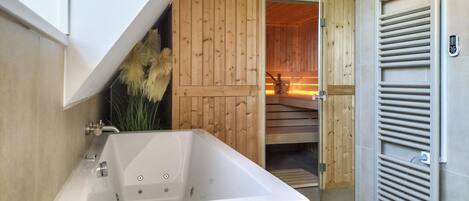 A bathroom with a bathtub, wooden walls, a wooden door, and a towel rack.