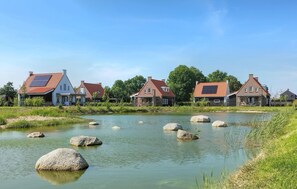 Un village riverain aux maisons traditionnelles, où l’on trouve une rivière paisible et de gros rochers dans l’eau.