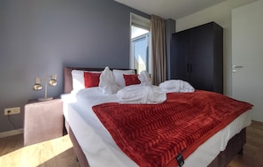 Ein Hotelzimmer mit Bett, Nachttisch, Schrank und einem Fenster mit Vorhängen.
