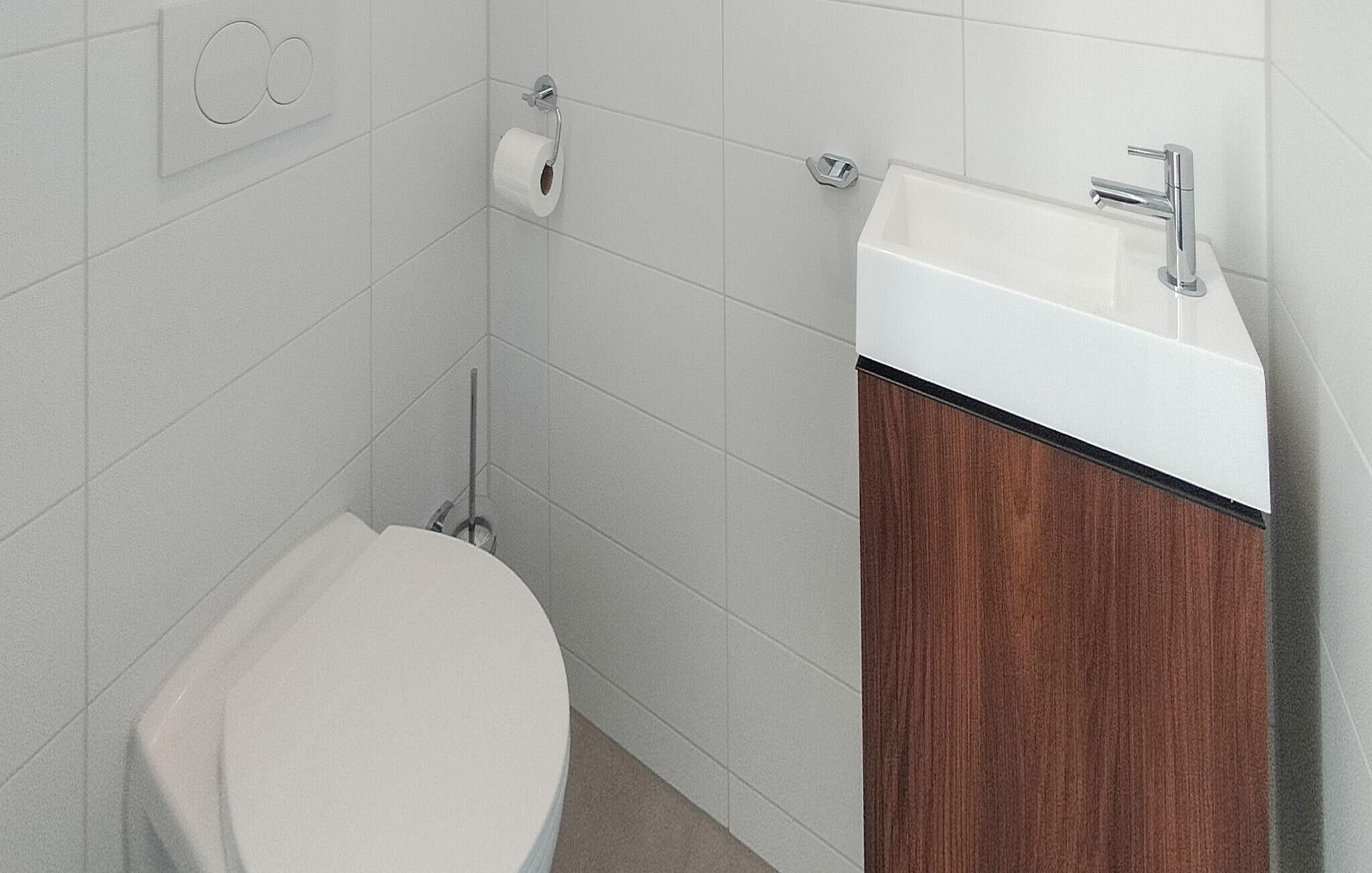 A bathroom with a toilet, a sink, and a mop.