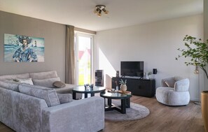 Ein modernes Wohnzimmer mit Sofa, Couchtisch, TV-Möbel und einem Sessel.