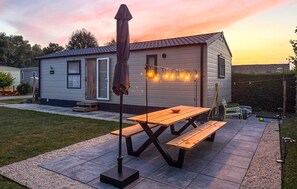 Un patio con tavolo e panche in legno, luci a stringa e un ombrellone.