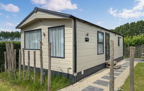 Una casa mobile a un piano con esterno beige, ampie finestre e un piccolo portico.