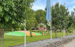 Un parco con prati verdi, un'asta sventolante e un edificio sullo sfondo.