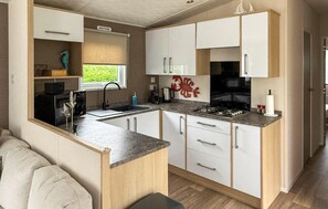 A compact kitchen with white cabinets, a sink, a stove, and a window. - Cozy home in Sint Kruis with WiFi (Sint Kruis)