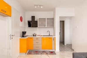 A compact kitchen with orange cabinets, a coffee machine, a sink, and a clock on the wall. - Beachside Villa Mia Apartment 2, Medveja, Croatia (Medveja)