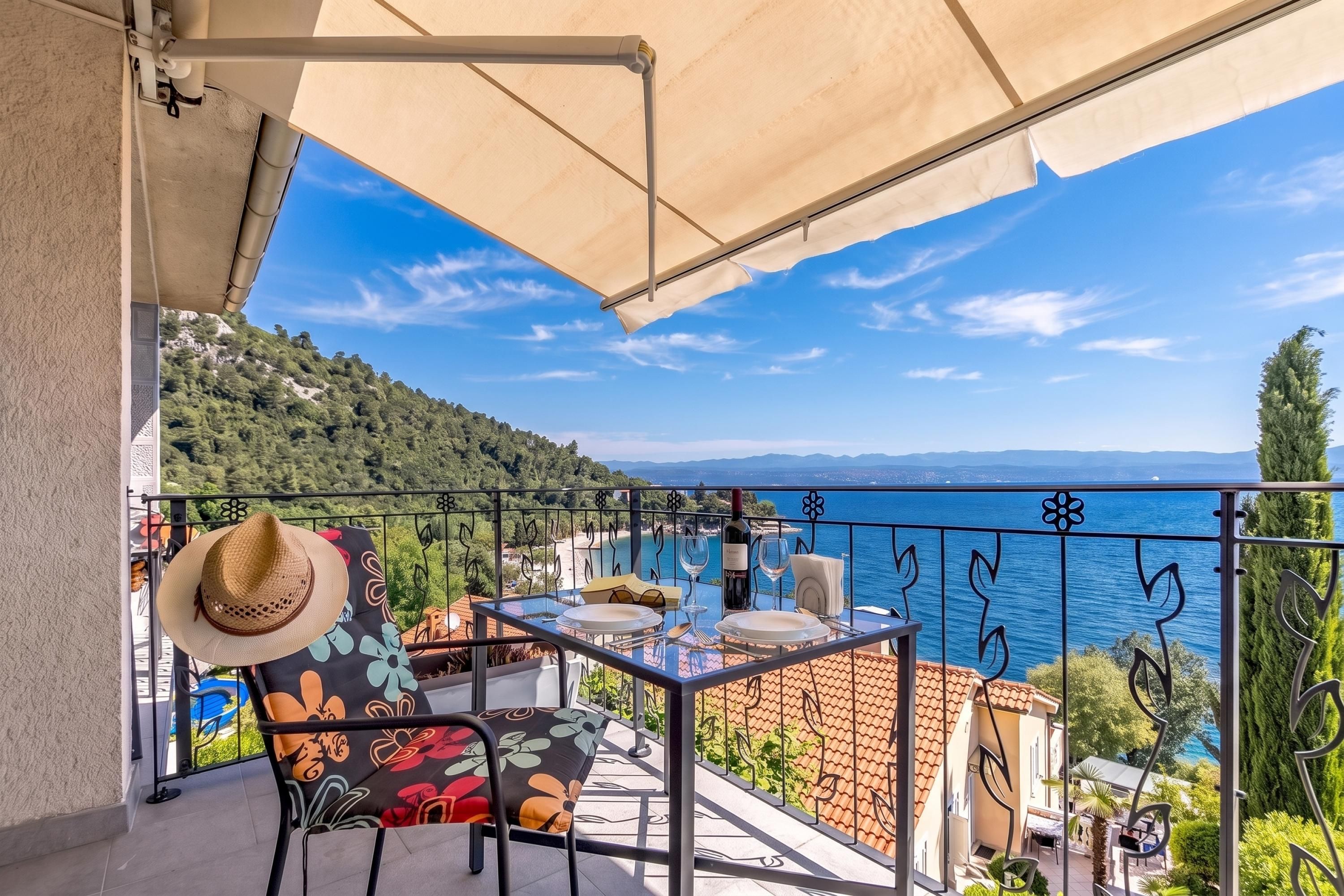 Un balcon avec une table dressée pour deux personnes, offrant une vue sur la côte.