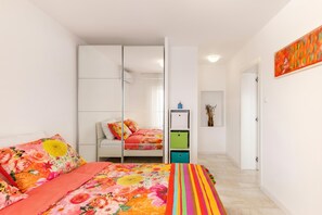 Ein Schlafzimmer mit Bett, Kleiderschrank, Schreibtisch und Spiegel.