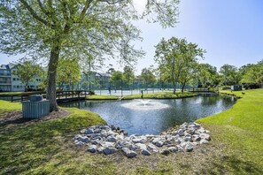 A park with a pond, trees, a wooden bridge, and a stone arrangement. - Cozy 2-bedroom condo in Myrtle Beach, Shore 2 Please (Myrtle Beach)