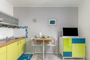 A compact kitchen with a dining table, chairs, a sink, and a cabinet with a TV. - Beachside Villa Mia Apartment 1, Medveja, Croatia (Medveja)