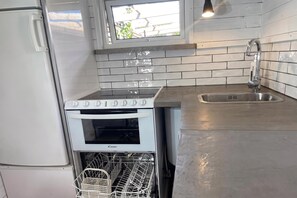 Eine kleine Küche mit eingebautem Backofen, Geschirrspüler und Spüle.