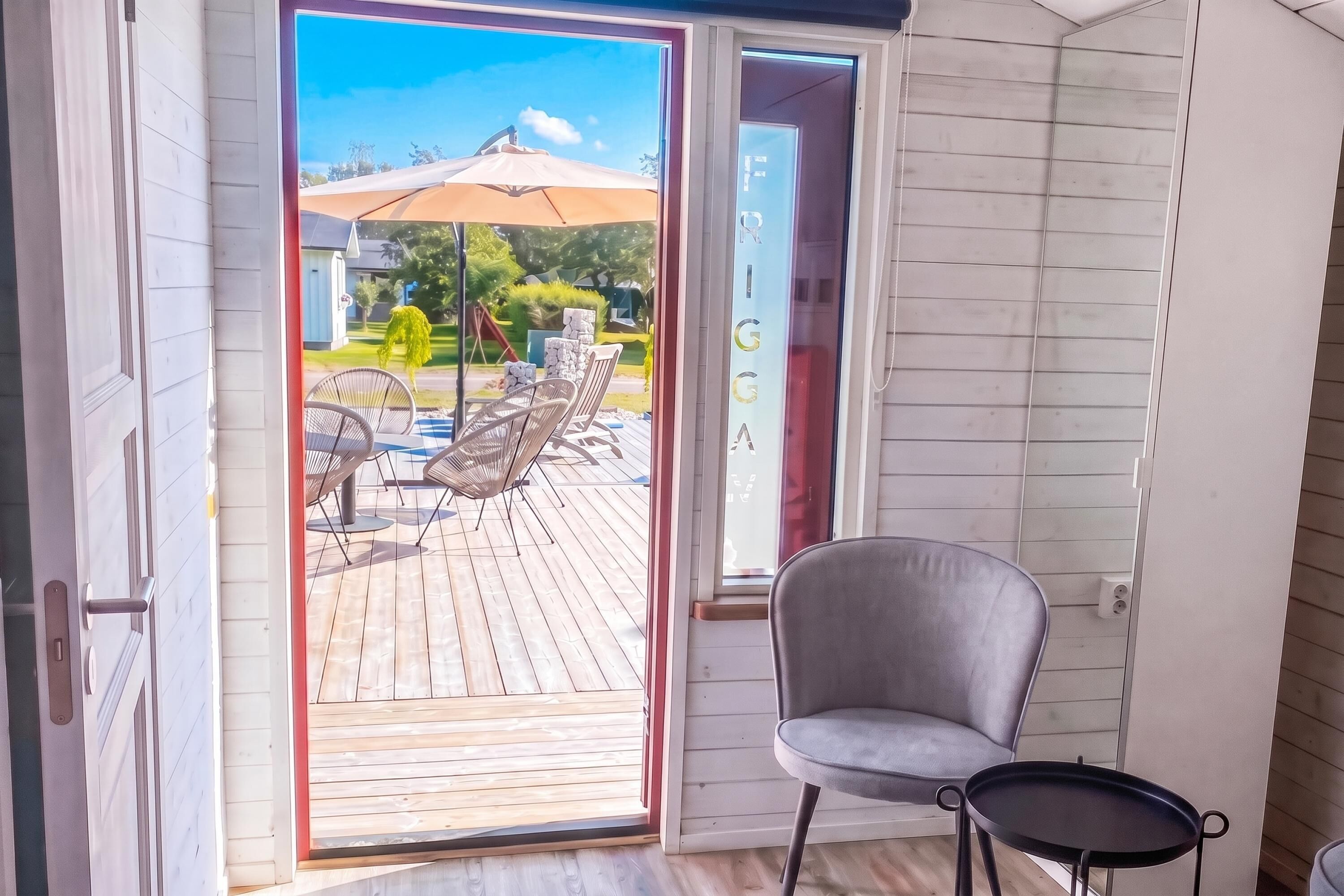 A room with a sliding glass door leading to an outdoor deck with a pool, lounge chairs, and a pergola.