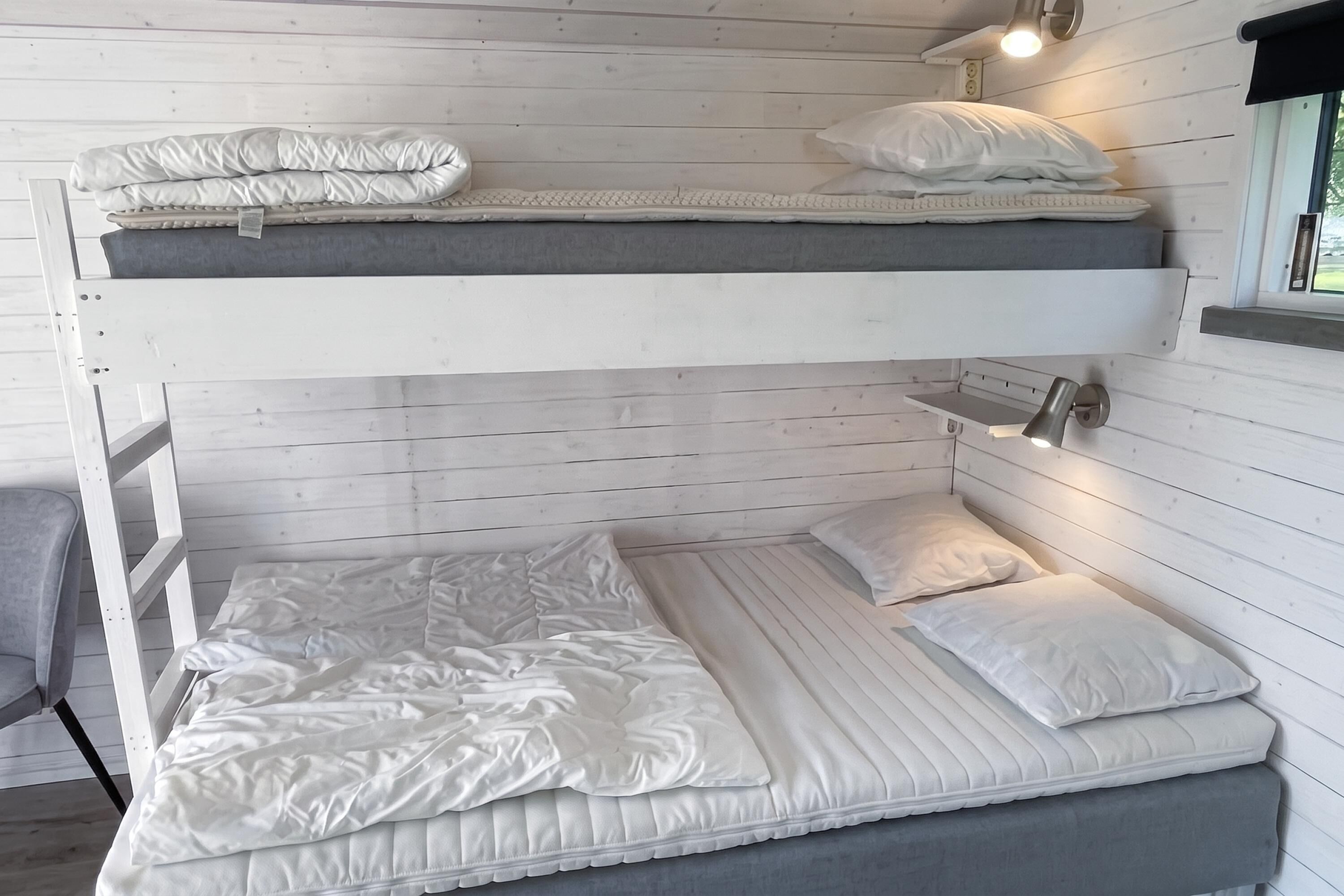 A bunk bed with a headboard and a bedside table with a lamp.