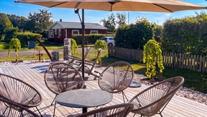 En udendørs terrasse med fletningsmøbler, et bord og en parasol.