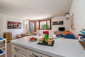 A kitchen with a dining area, a TV, and a window with a view. - Ladunia 2, Marinella, Italy (Marinella)