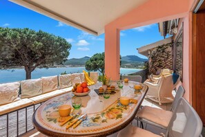 A dining area with a table set for four, overlooking a scenic view of the sea and mountains. - Casa Titta, Marinella, Italy (Marinella)