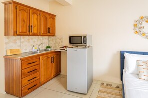 Una cocina compacta con armarios de madera, un microondas y un refrigerador.