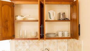 Eine Küche mit Holzausstattung, einem Wasserkocher, einem Toaster sowie Geschirr und Gläsern.