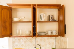Una cocina con armarios de madera, un hervidor, una tostadora y diferentes platos y vasos.