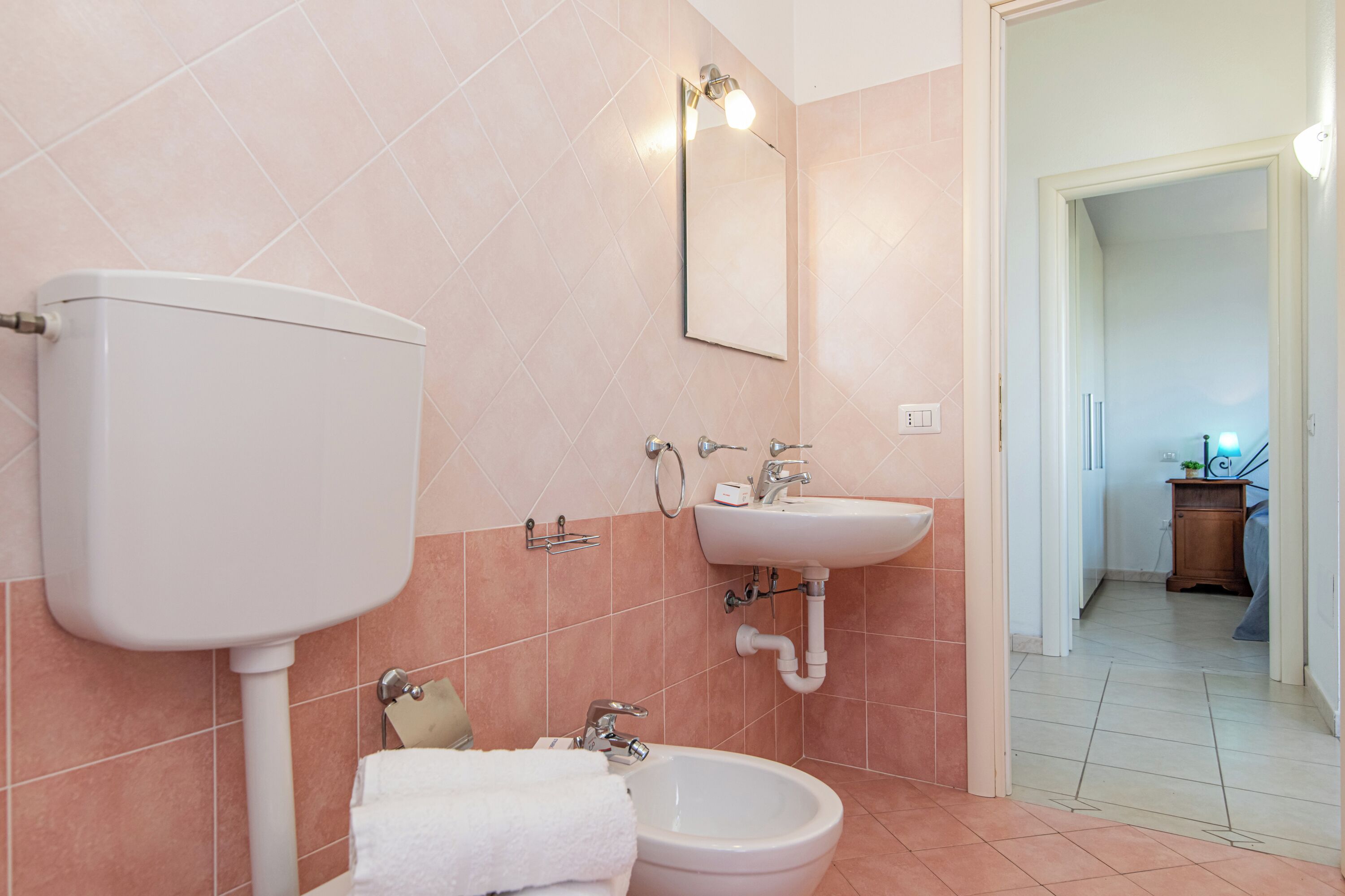 Un bagno con il water, bidet, lavandino e specchio.