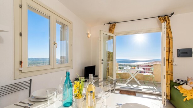 Un balcon avec une table dressée pour le dîner, un canapé et une vue sur le paysage.
