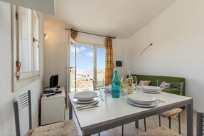 A dining area with a table set for four, a green upholstered headboard, and a view through the open door. - Elicriso, San Pasquale, Italy (San Pasquale)