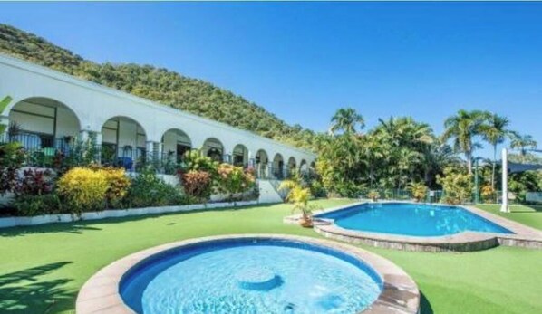 A hotel with a swimming pool, a covered outdoor area with arches, and a hillside backdrop. - 71 Mandalay : Deluxe Studio (Nelly Bay)