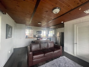 A modern kitchen with white cabinets, a brown leather couch, and a gray rug. - Hotel Style Lakeview Cottage • 3BR • Heated Pool (Lake Wales)