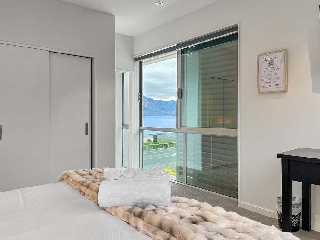 Een moderne slaapkamer met een groot raam, een bed met een bontdeken en uitzicht op het omliggende landschap.